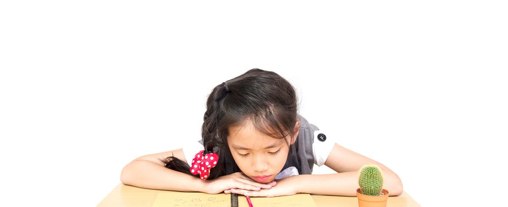 Seorang anak sedang ketiduran setelah belajar di meja